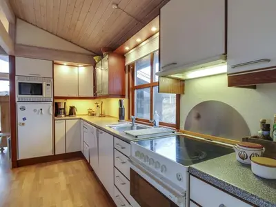 a large kitchen with white appliances and wooden floors at Holiday Home Essie - 250m from the sea by Interhome in Løkken