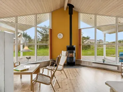 a living room with a table and chairs and windows at Holiday Home Aleta - 500m from the sea by Interhome in Løkken