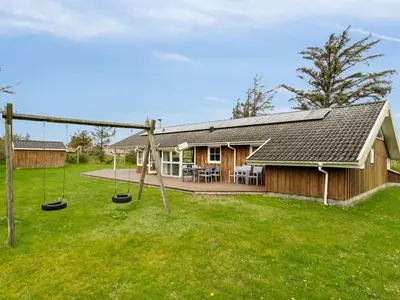 a house with swings in the yard at Holiday Home Aleta - 500m from the sea by Interhome in Løkken