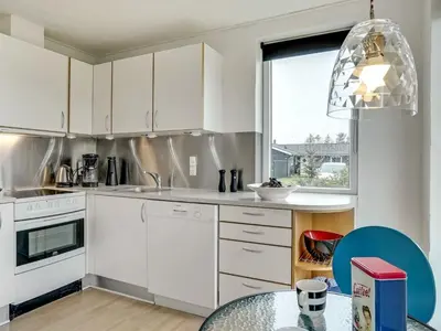 a kitchen with white cabinets and a glass table at Holiday Home Dome - 750m from the sea by Interhome in Løkken