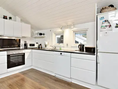 a kitchen with white cabinets and a refrigerator at Holiday Home Annalisa - 1-2km from the sea by Interhome in Løkken
