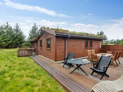 a cabin with a deck with a table and chairs at Holiday Home Jo - 1-2km from the sea by Interhome in Løkken