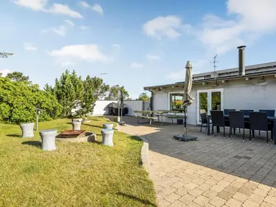 a patio with chairs and an umbrella in a yard at Holiday Home Lenni - 700m from the sea by Interhome in Løkken