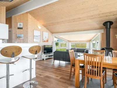 a kitchen and living room with a table and chairs at Holiday Home Katla - 400m from the sea by Interhome in Løkken
