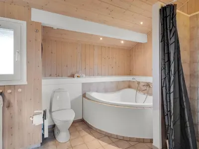 a bathroom with a tub and a toilet and a sink at Holiday Home Katla - 400m from the sea by Interhome in Løkken