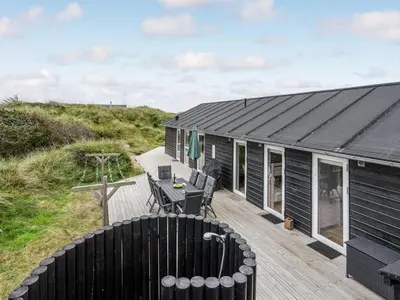 a black tiny house with a wooden deck at Holiday Home Marthine - 200m from the sea by Interhome in Løkken