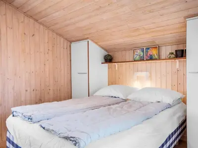 a bed in a room with a wooden wall at Holiday Home Ofrath - 350m from the sea by Interhome in Løkken