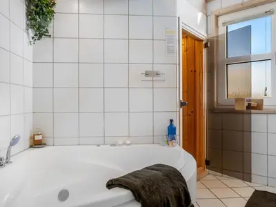 a white bathroom with a tub and a window at Holiday Home Ofrath - 350m from the sea by Interhome in Løkken