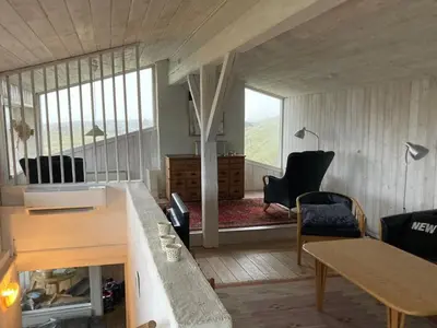 a living room with a table and chairs and a large window at Holiday Home Trude - 250m from the sea by Interhome in Løkken