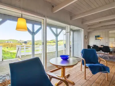 a living room with a table and chairs and a view of the ocean at Holiday Home Trude - 250m from the sea by Interhome in Løkken
