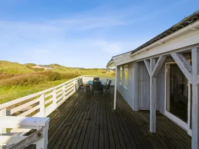 a house with a deck with a table and chairs at Holiday Home Trude - 250m from the sea by Interhome in Løkken