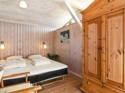 a bedroom with a bed and a wooden wall at Holiday Home Trude - 250m from the sea by Interhome in Løkken