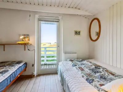 a bedroom with two beds and a sliding glass door at Holiday Home Trude - 250m from the sea by Interhome in Løkken