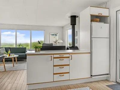 a kitchen with a white refrigerator and a living room at Holiday Home Thorfrid - 150m from the sea by Interhome in Løkken