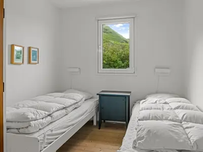 two beds in a white room with a window at Holiday Home Thorfrid - 150m from the sea by Interhome in Løkken