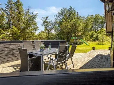 a patio with a table and chairs on a deck at Holiday Home Gullborg - 800m from the sea by Interhome in Løkken