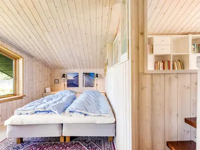 a bed in a room with a wooden ceiling at Holiday Home Gullborg - 800m from the sea by Interhome in Løkken