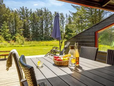 a picnic table with a basket of fruit on a deck at Holiday Home Gullborg - 800m from the sea by Interhome in Løkken