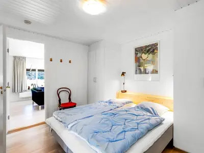 a bedroom with a large bed and a red chair at Holiday Home Gullborg - 800m from the sea by Interhome in Løkken