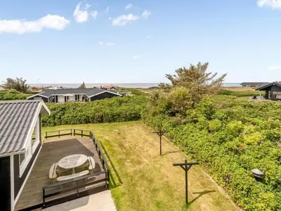 a backyard with a deck with a table and chairs at Holiday Home Bengta - 200m from the sea by Interhome in Løkken