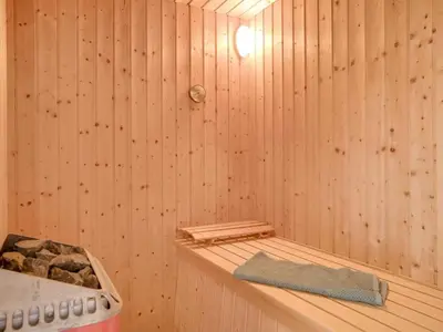 a wooden sauna with a towel on a shelf at Holiday Home Bengta - 200m from the sea by Interhome in Løkken