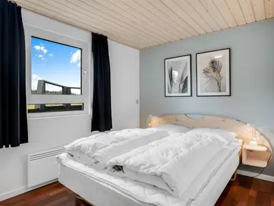 a white bedroom with a bed and a window at Holiday Home Bengta - 200m from the sea by Interhome in Løkken