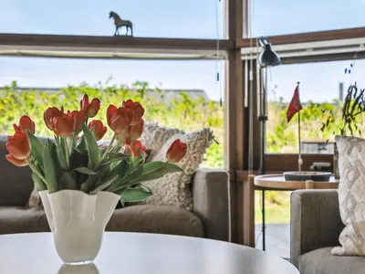 a vase with red tulips on a table in a living room at Holiday Home Danica - 175m from the sea by Interhome in Løkken
