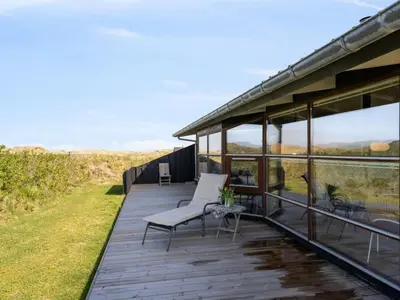 a house with a deck with chairs and windows at Holiday Home Danica - 175m from the sea by Interhome in Løkken