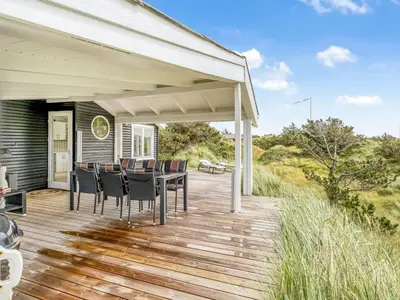 a wooden deck with a table and chairs on a house at Holiday Home Stina - 250m from the sea by Interhome in Løkken