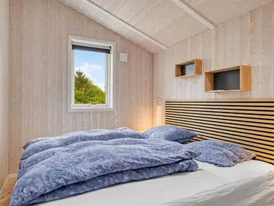 a bedroom with a large bed with blue pillows at Holiday Home Dimo - 700m from the sea by Interhome in Løkken