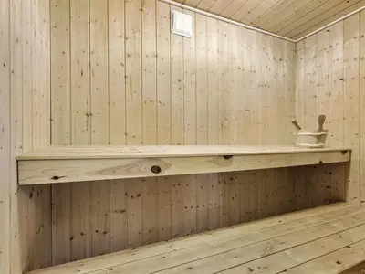 a wooden sauna with a shelf on the wall at Holiday Home Solvejg - 150m from the sea by Interhome in Løkken