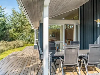 a deck with a table and chairs on a house at Holiday Home Terho - 1km from the sea by Interhome in Løkken