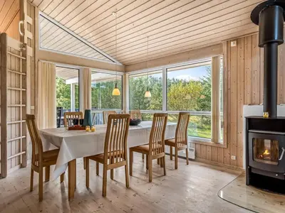 a dining room with a table and chairs and a fireplace at Holiday Home Terho - 1km from the sea by Interhome in Løkken