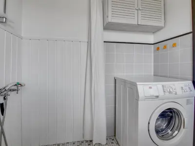 a washer and dryer in a small bathroom at Holiday Home Tulir - 300m from the sea by Interhome in Løkken