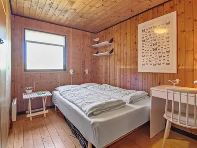 a bedroom with a bed in a wooden wall at Holiday Home Tulir - 300m from the sea by Interhome in Løkken