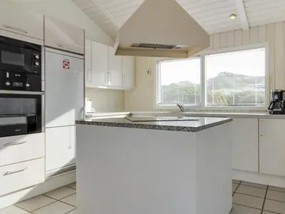 a kitchen with white appliances and a large window at Holiday Home Avni - 200m from the sea by Interhome in Løkken