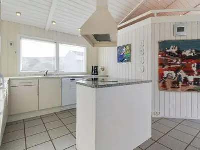 a white kitchen with a counter top and a sink at Holiday Home Avni - 200m from the sea by Interhome in Løkken