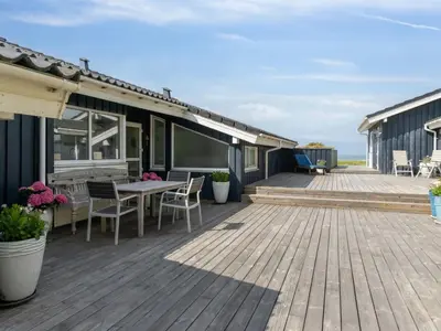 a deck with a table and chairs on a house at Holiday Home Alyssa - 300m from the sea by Interhome in Løkken
