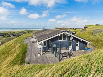a blue house on a hill with a wooden deck at Holiday Home Alyssa - 300m from the sea by Interhome in Løkken