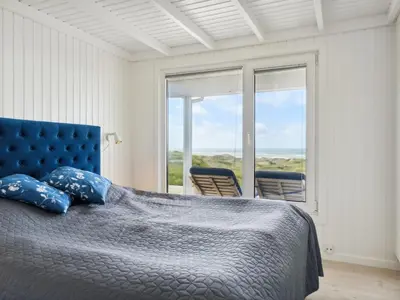 a bedroom with a bed and a window with chairs at Holiday Home Alyssa - 300m from the sea by Interhome in Løkken