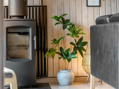 a living room with a fireplace and a potted plant at Holiday Home Seda - 600m from the sea by Interhome in Løkken