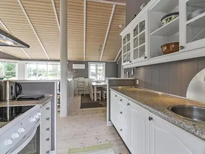 a kitchen with white cabinets and a wooden ceiling at Holiday Home Jens - 425m from the sea by Interhome in Løkken
