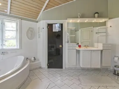 a white bathroom with a tub and a sink at Holiday Home Jens - 425m from the sea by Interhome in Løkken