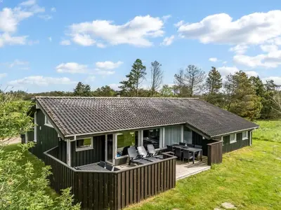a green cottage with a deck and patio at Holiday Home Aponi - 400m from the sea by Interhome in Løkken