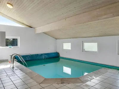 a swimming pool in a room with a wooden ceiling at Holiday Home Aponi - 400m from the sea by Interhome in Løkken