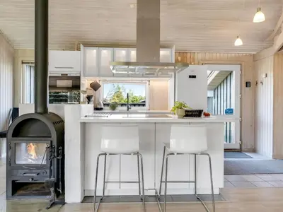 a kitchen with a stove and a counter with stools at Holiday Home Aponi - 400m from the sea by Interhome in Løkken