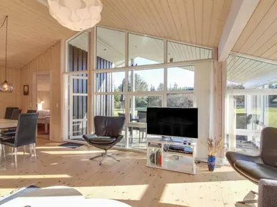 a living room with a flat screen tv and chairs at Holiday Home Nynke - 600m from the sea by Interhome in Løkken