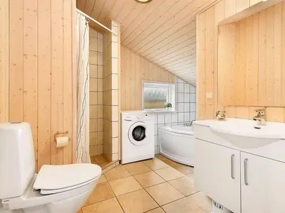 a bathroom with a toilet sink and a washing machine at Holiday Home Nynke - 600m from the sea by Interhome in Løkken