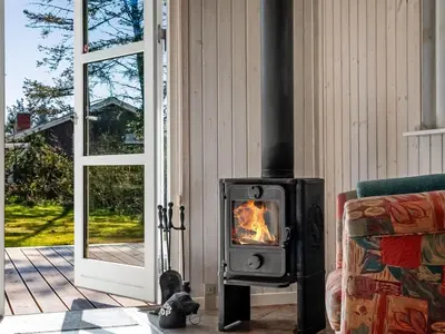 a wood stove in a living room next to a door at Holiday Home Troels - 750m from the sea by Interhome in Løkken