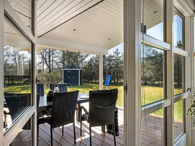 a screened porch with a table and chairs at Holiday Home Troels - 750m from the sea by Interhome in Løkken